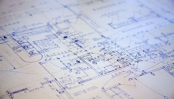 Primer plano de un plano arquitectónico en tonos azules, con líneas y detalles de diseño técnico sobre papel.